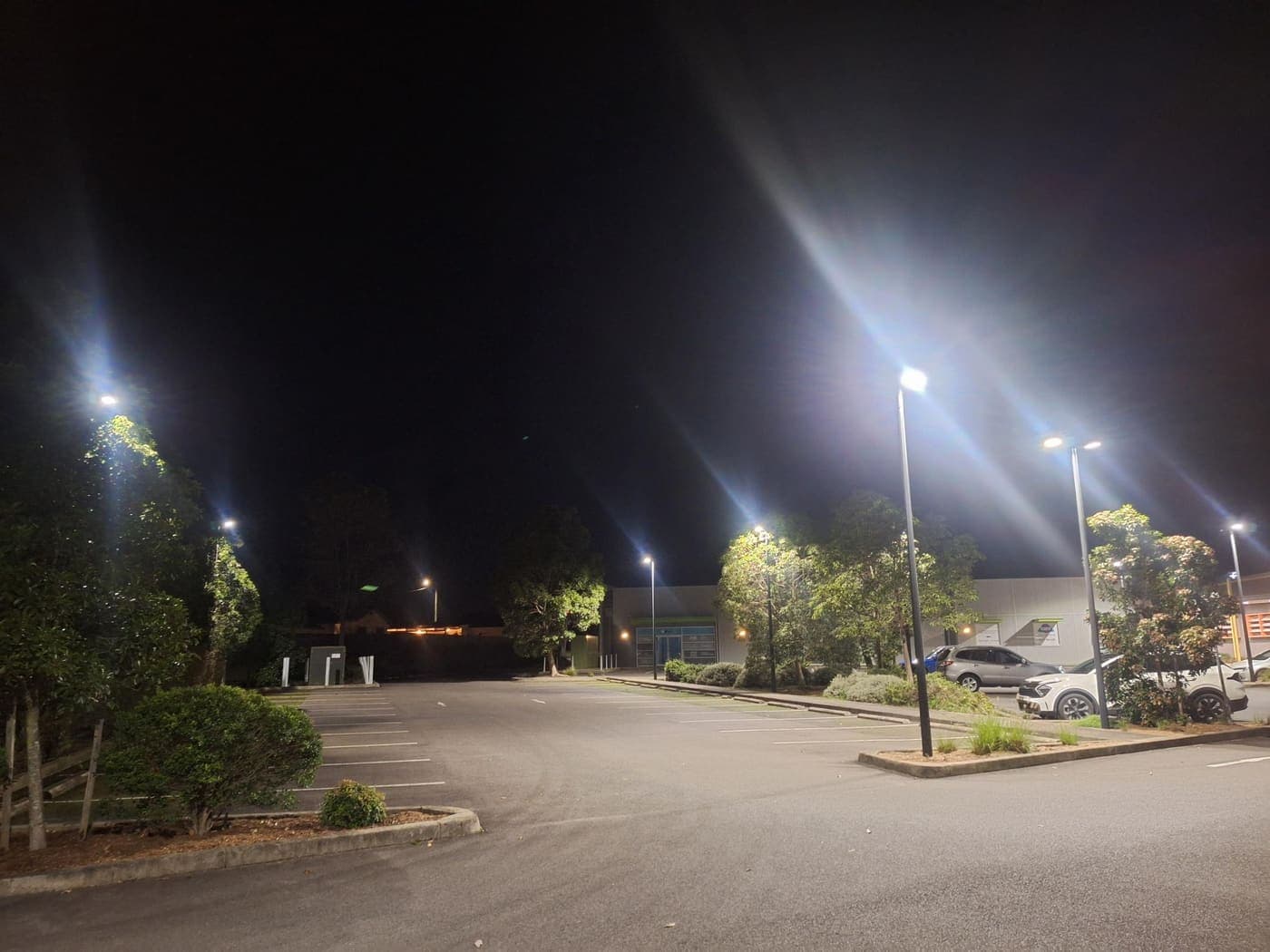 Commercial car park illuminated by tall LED pole lights at night