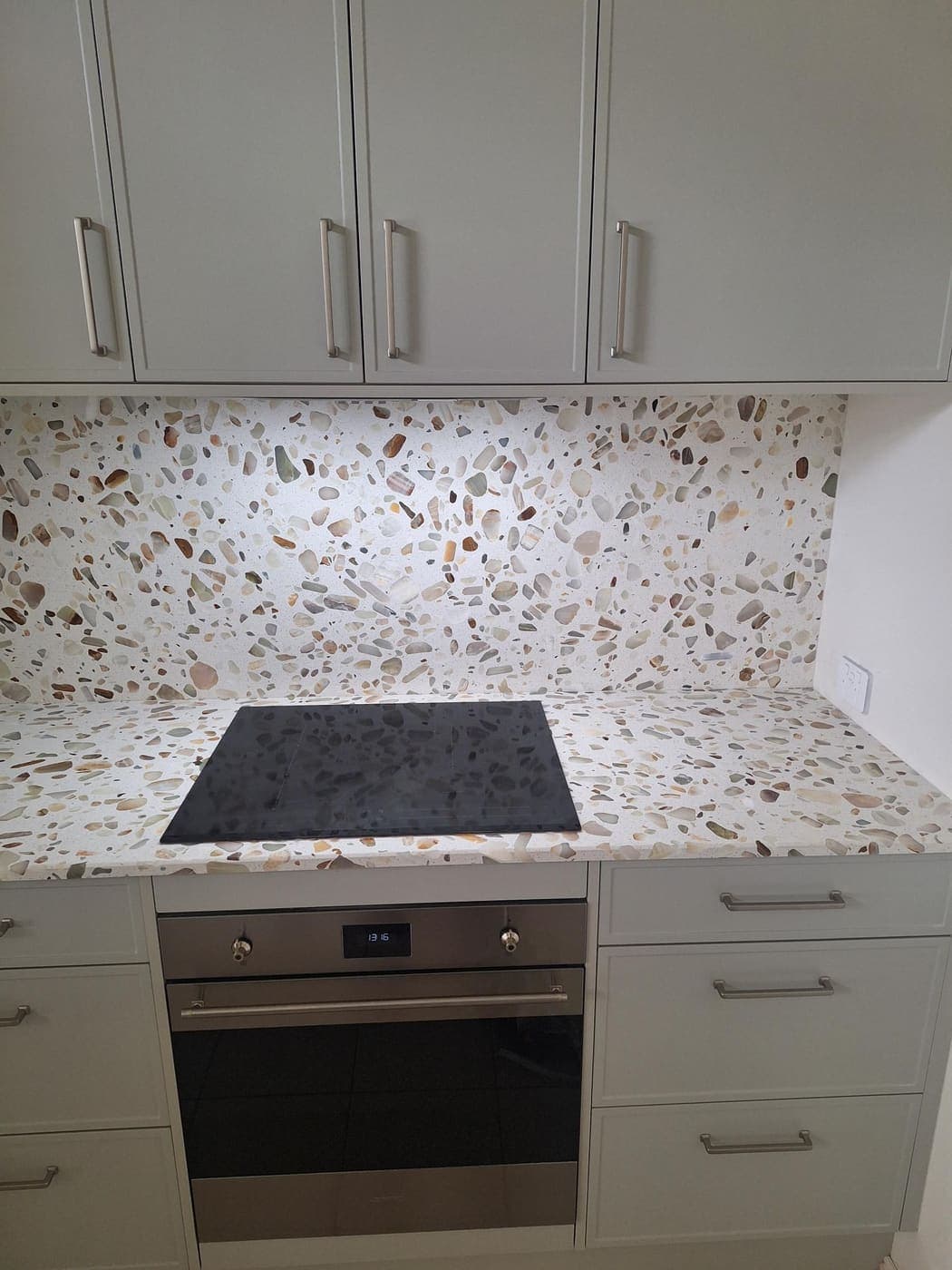 Kitchen with a terrazzo pebble splashback and stainless steel wall oven