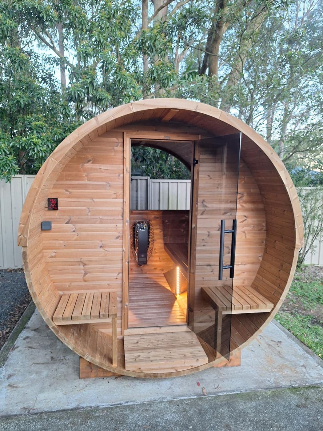 Outdoor timber barrel sauna with interior LED lighting and a wired sauna heater
