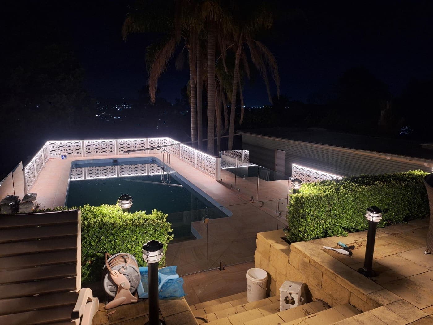 Poolside wall lit with LED strip lighting and bollard path lights at night