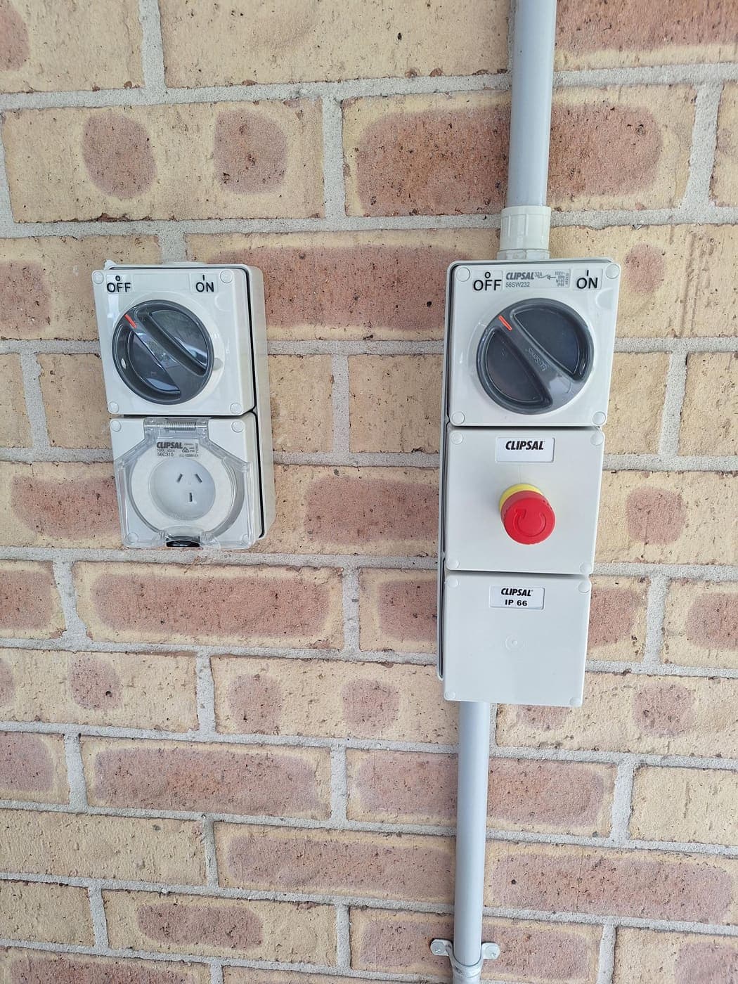 Weatherproof isolator switches, emergency stop and outdoor power point on a brick wall