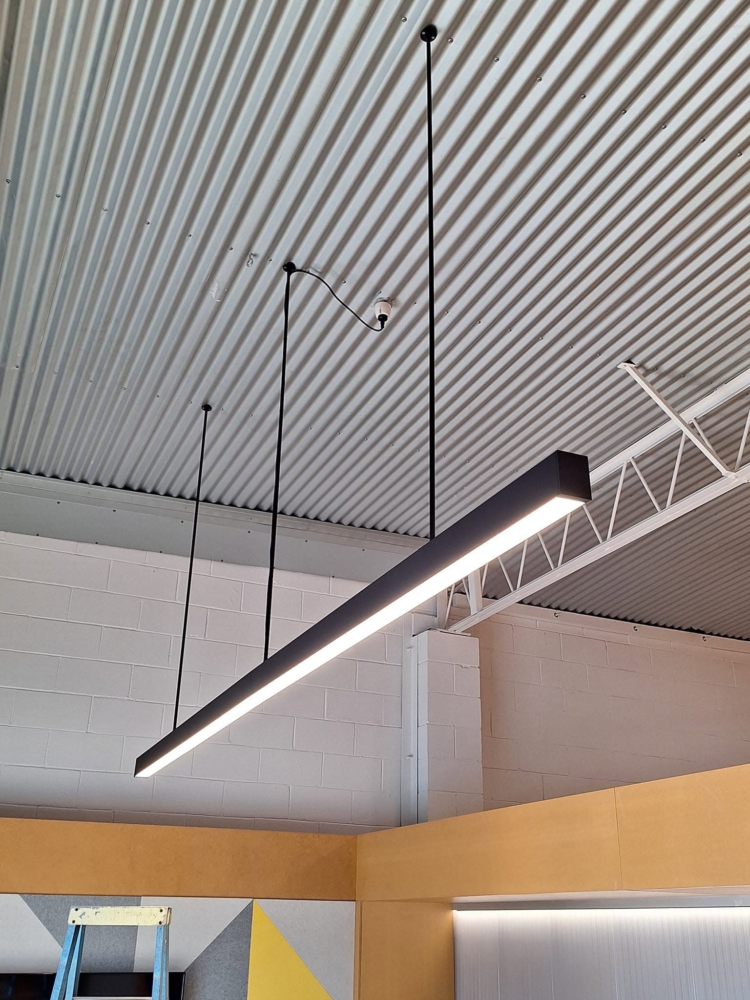 Long linear feature pendant light suspended over a commercial bar