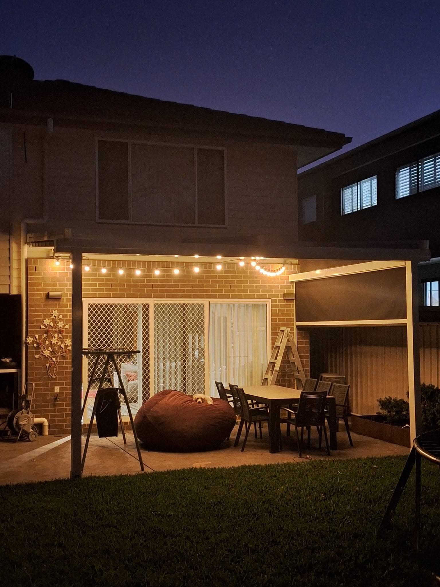 Festoon string lights strung over a backyard patio at dusk